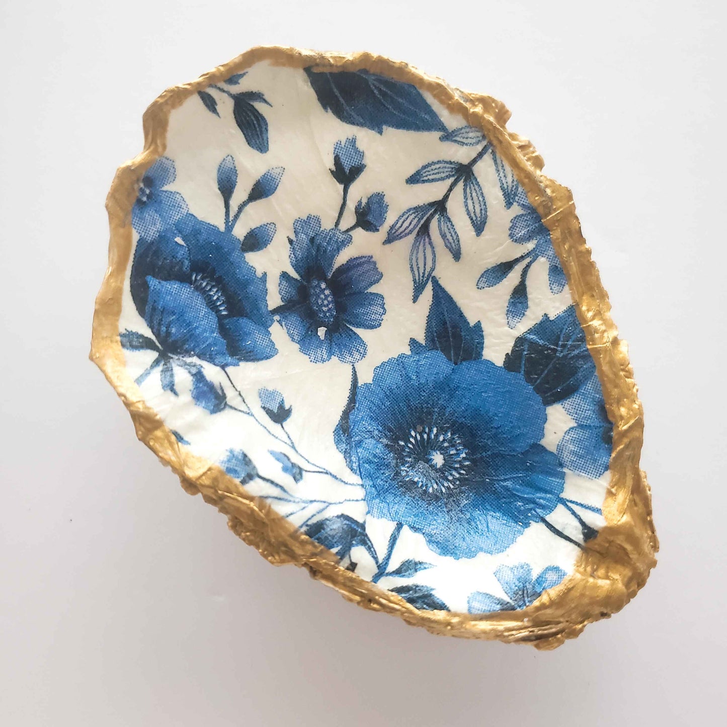 Decorative dish with blue floral design and gold rim on a white background