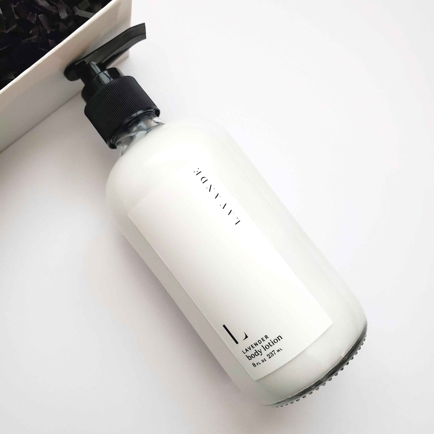 White bottle of lavender body lotion with black pump on a white background