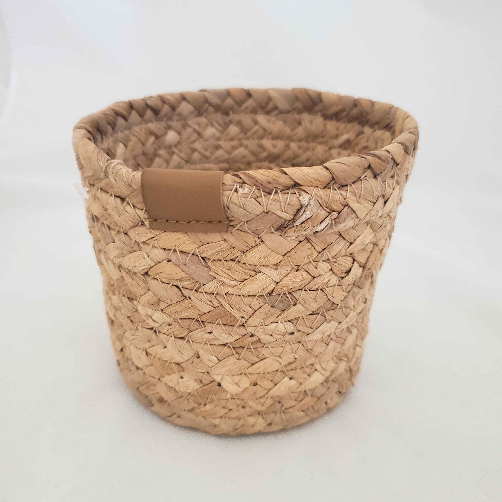 Woven basket with a brown leather patch on a white background