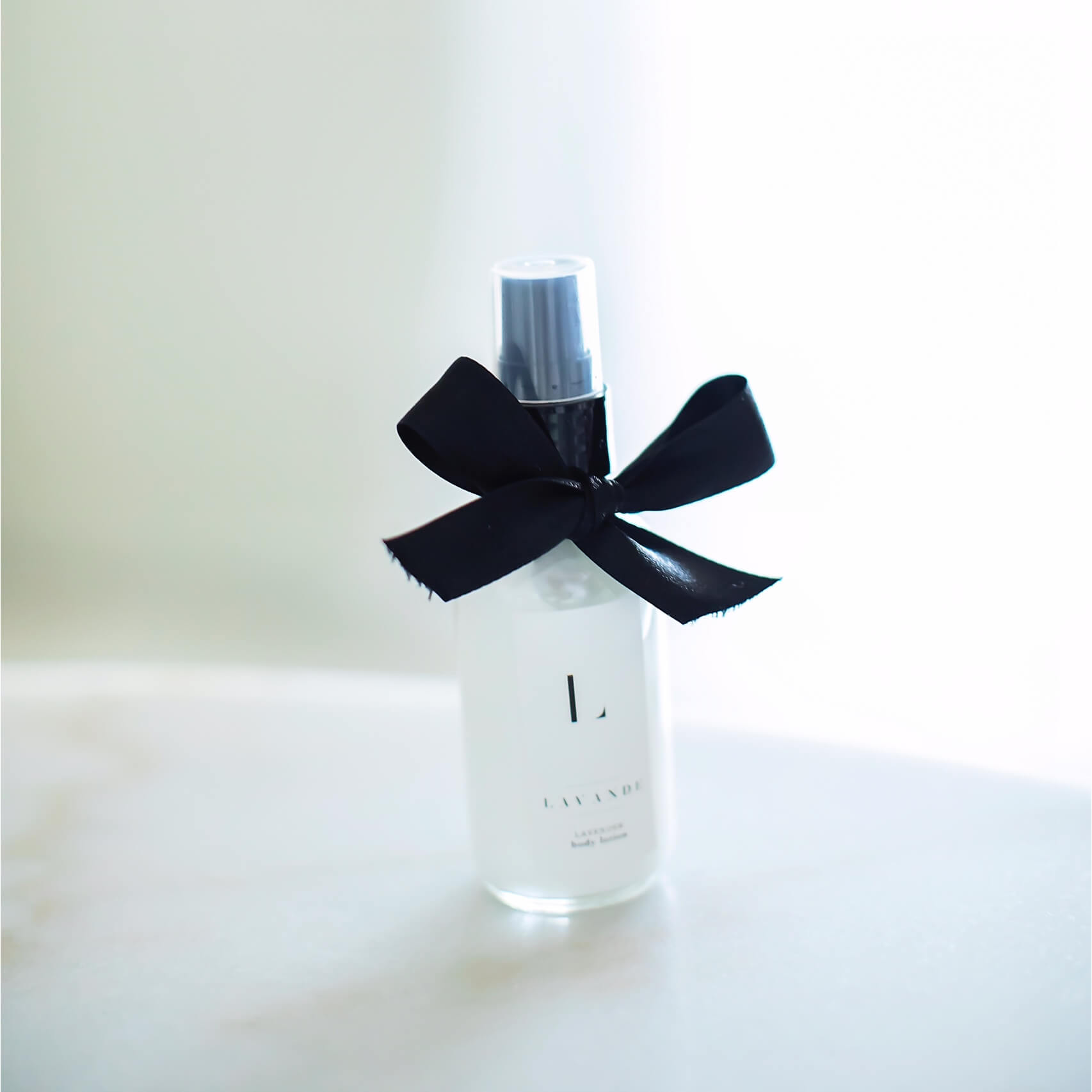 A travel size bottle of lavender lotion with a black bow