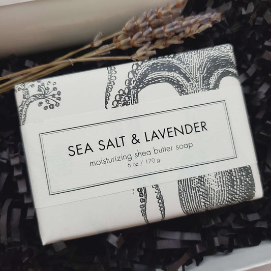 A 6 ounce sea salt and lavender Shea butter bar soap packaged in black and white paper with botanical and vintage illustrations.