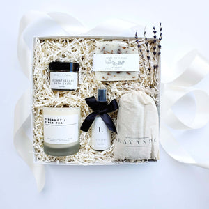 A self-care lavender gift box by The Gift Veil with a neutral color palette. Includes lavender soap, lotion, aromatherapy bath salts, a lavender sachet and a bergamot and black tea soy candle.