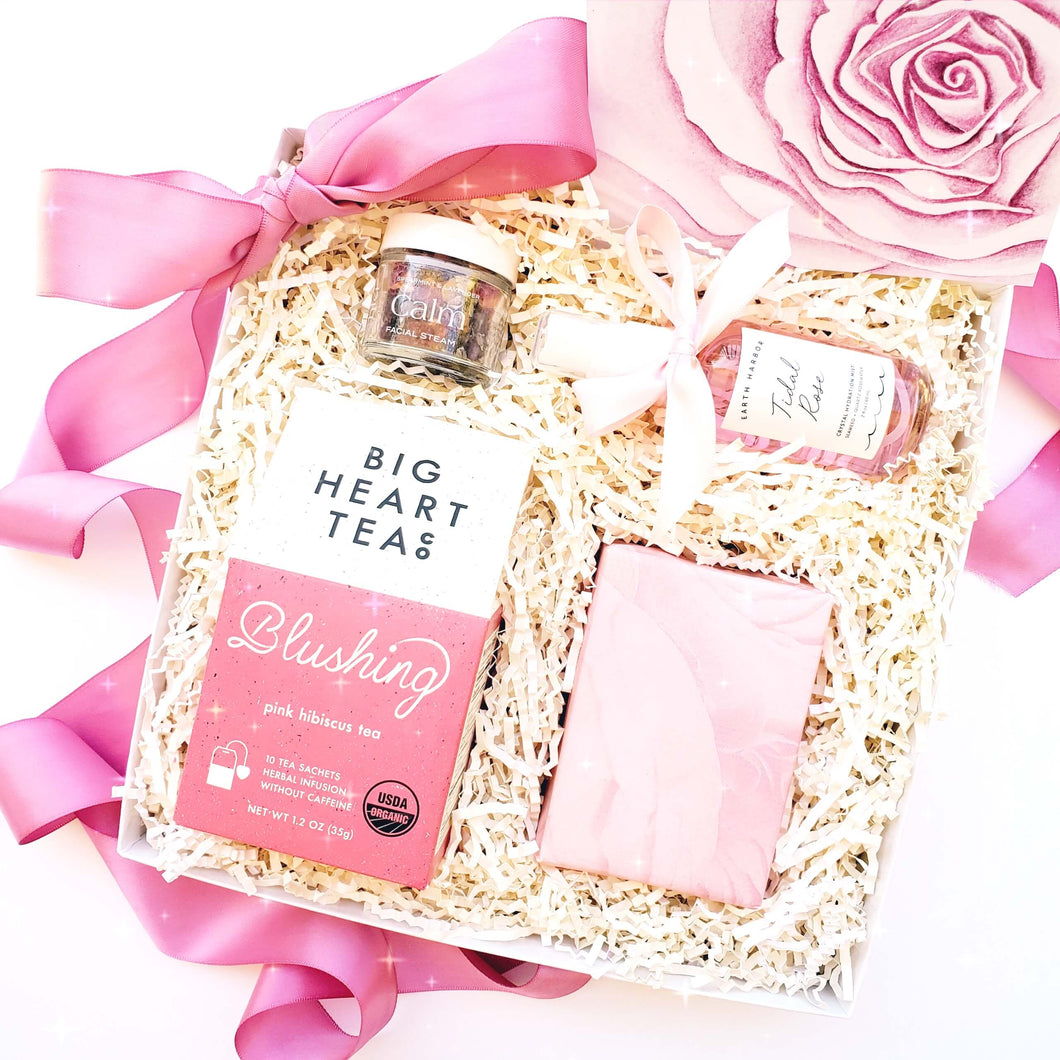 A gift box featuring the color pink by The Gift Veil. Gift box includes pink hibiscus tea, rose facial soap, rose face mist, floral facial steam and a pink rose notecard perfect for a bridesmaid gift or bride to be gift.