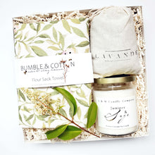 Load image into Gallery viewer, A housewarming gift box by The Gift Veil featuring a hand-poured juniper and sage candle, a flour sack towel with green spring leaves print and a lavender sachet.
